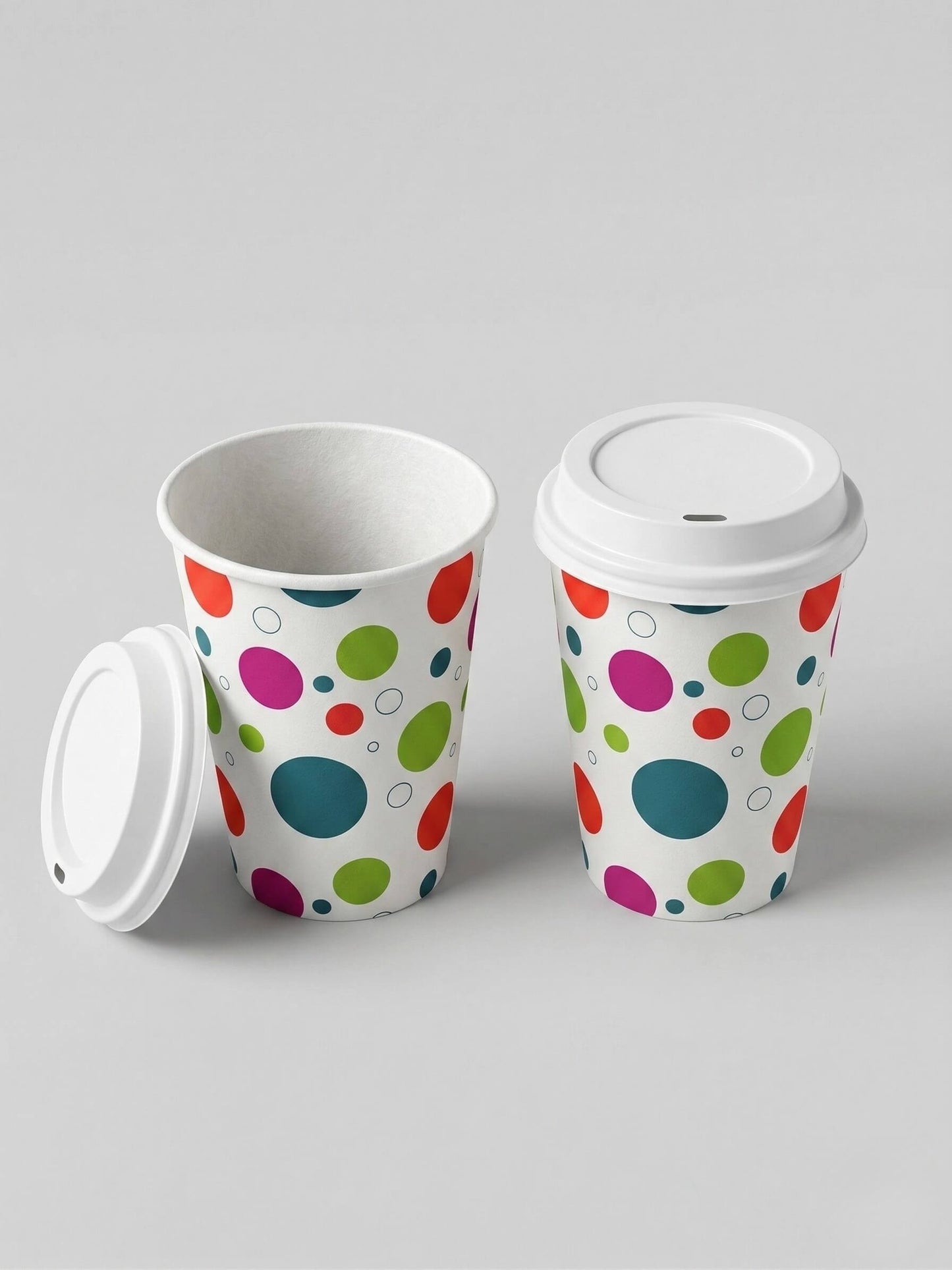 Two Axxion 12-ounce disposable paper cups featuring a polka dot pattern, displayed against a light grey background. One cup has a white travel lid securely attached, while the other is open with its lid leaning against the base. These sets are packaged in 6-count packs and distributed as 288 per case.